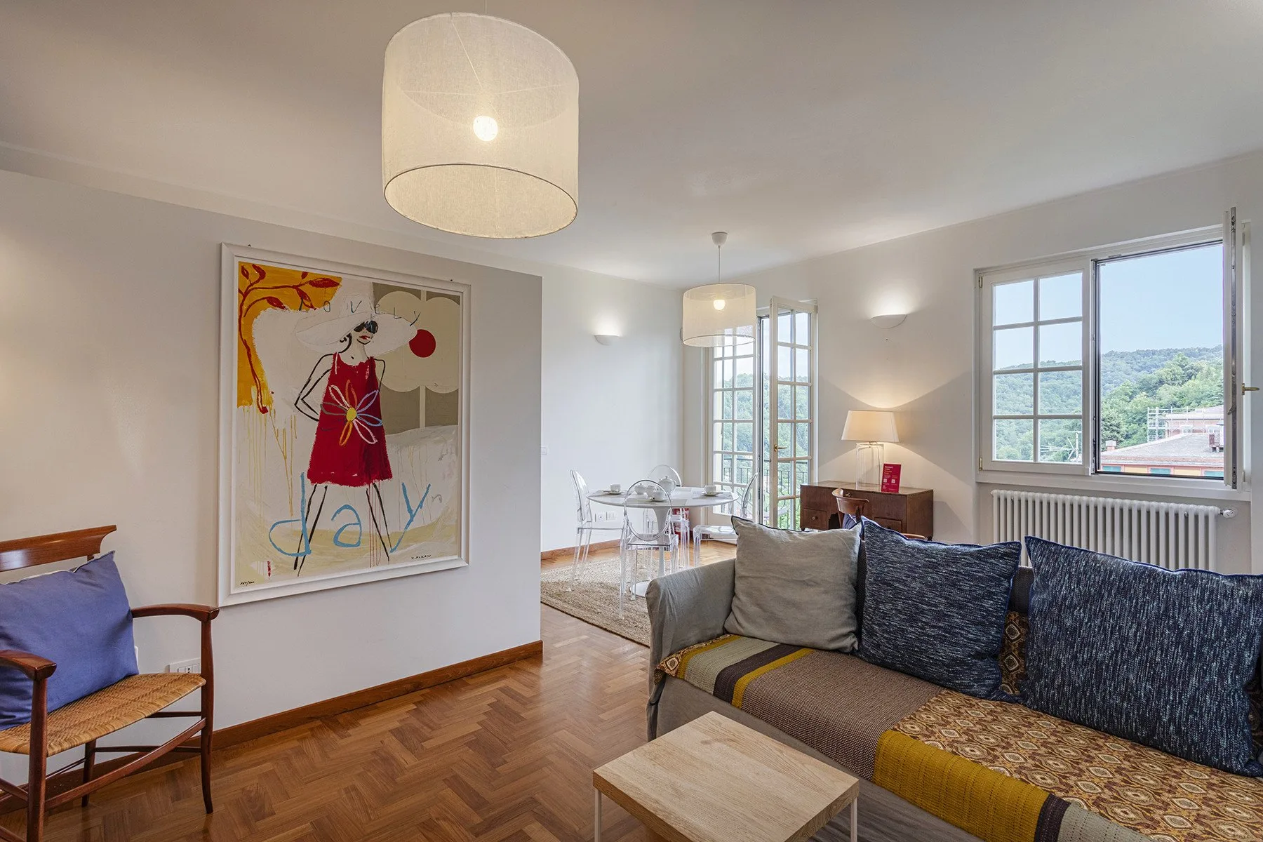 A bright living room with a sofa, dining table, and large windows.