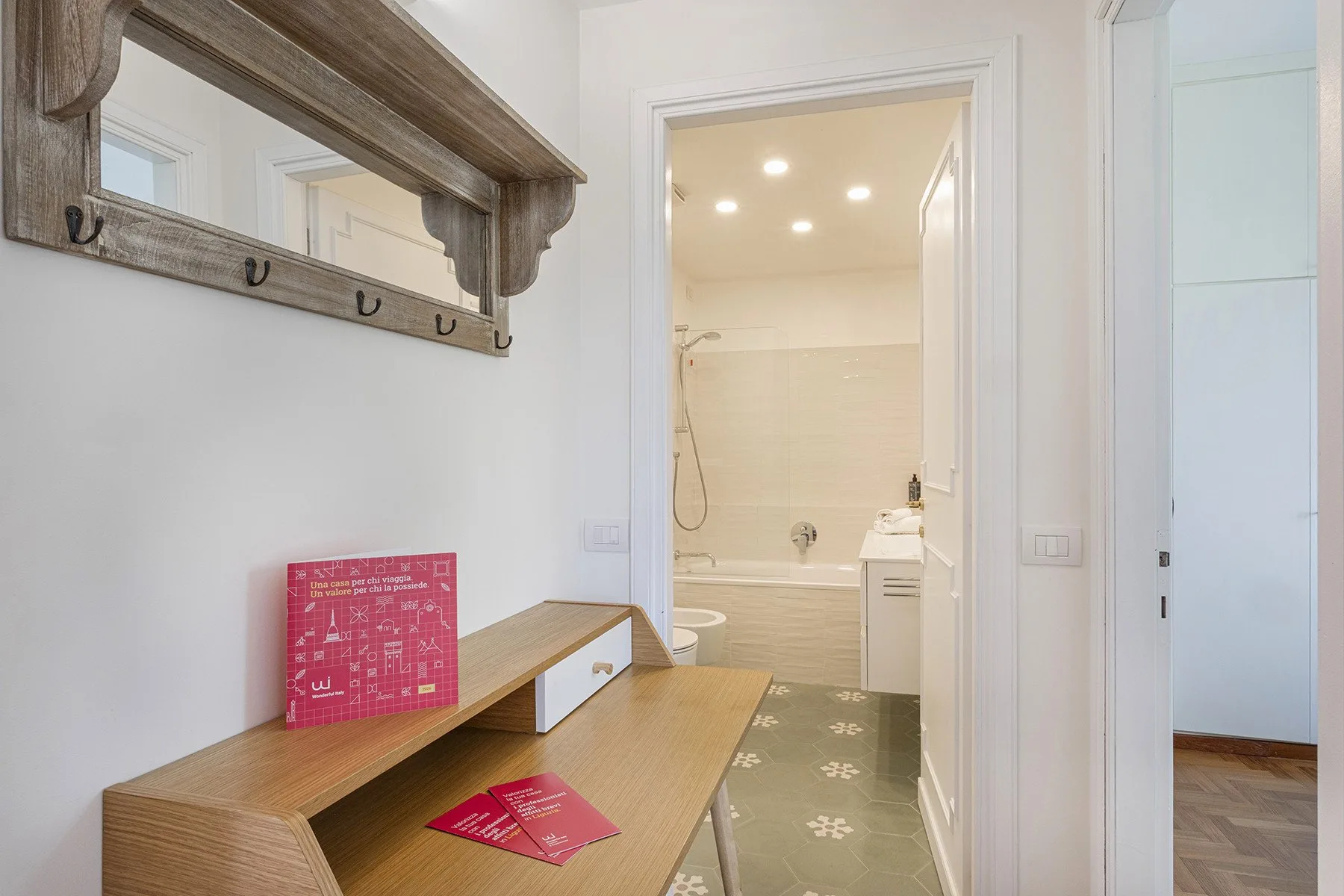 A hallway with a wooden console and a view into a bathroom.