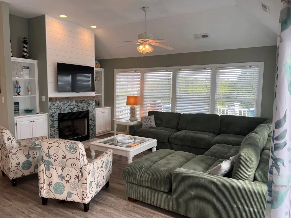 A living room with a large sectional sofa, patterned armchairs, and a fireplace.