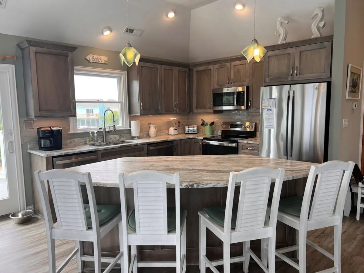 A spacious kitchen with dark cabinets, stainless steel appliances, and an island with seating.