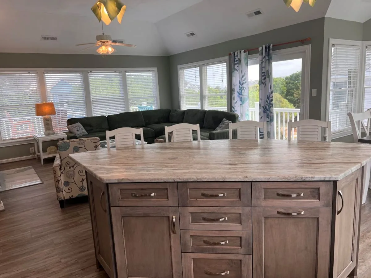 A spacious living and dining area with a large kitchen island, seating, and windows.