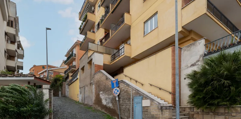 A narrow cobblestone street runs between apartment buildings and a stairway.