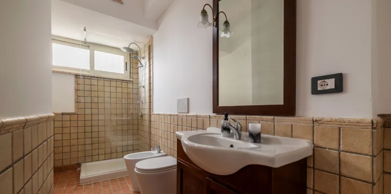 A tiled bathroom with a sink, toilet, and glass shower area.