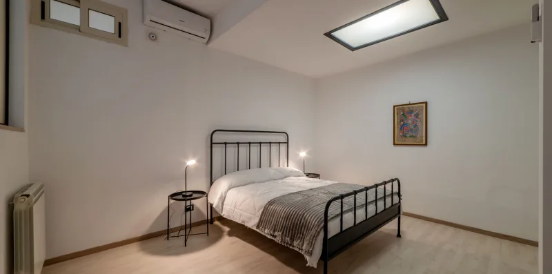 A bedroom with a black metal bed, bedside table, and framed wall art.