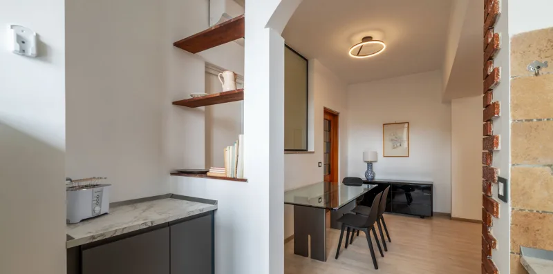 A dining area with a table and chairs sits beside a compact kitchen.