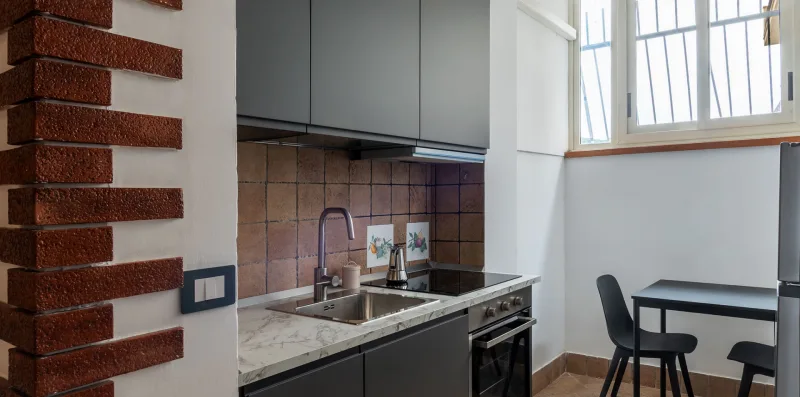 A compact kitchen with a sink and cooktop beside a small dining table.