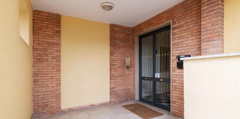 A brick entryway with a black metal gate and tiled floor.