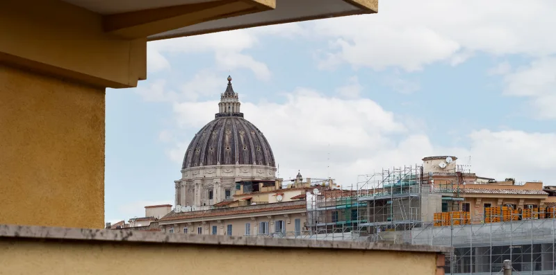 Un edificio emblemático con cúpula se alza sobre los tejados de la ciudad bajo un cielo nublado.
