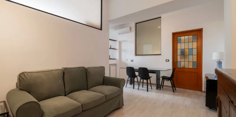 A living room with seating and a dining table beside a wooden door.