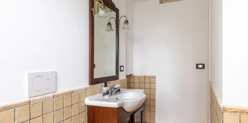 A bathroom vanity with a sink and mirror above tiled walls.