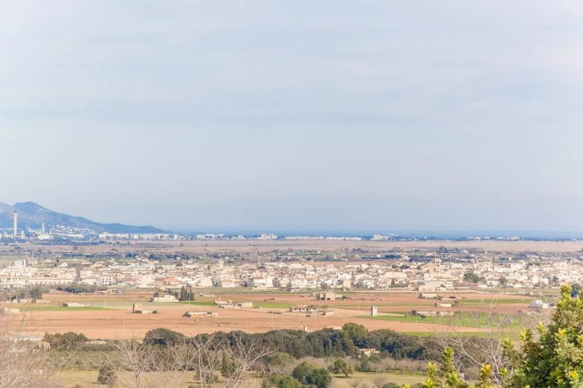 A broad landscape view shows a coastal city, fields, and distant hills.