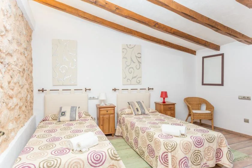 A bedroom with two beds and exposed wooden ceiling beams.