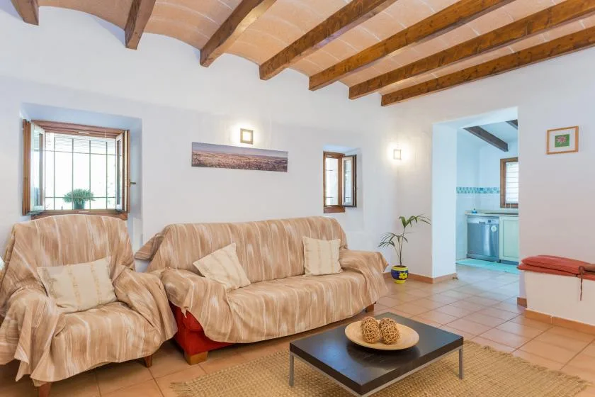A living room with seating around a low coffee table and an open doorway to a kitchen.