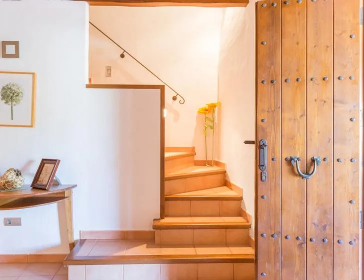 An interior entryway with a wooden staircase and a large wooden door.