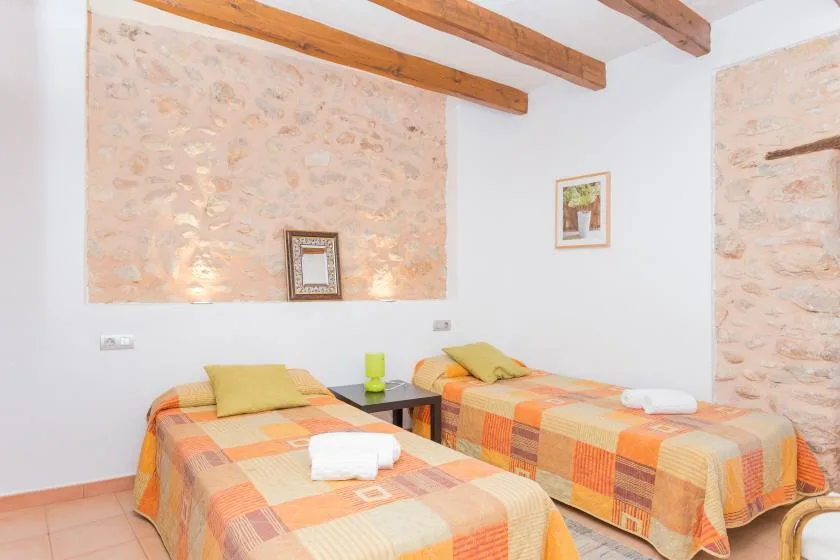 A twin bedroom with two beds covered in orange and yellow patterned bedding.