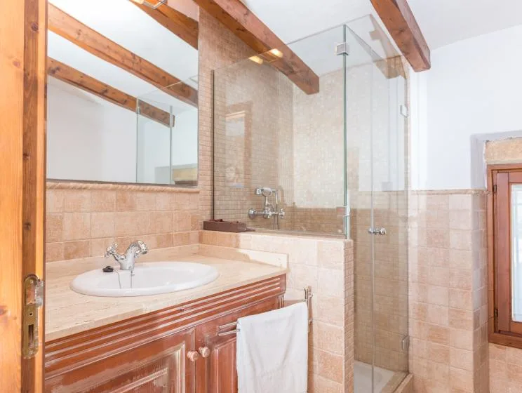 A tiled bathroom with a sink, mirror, and glass shower.