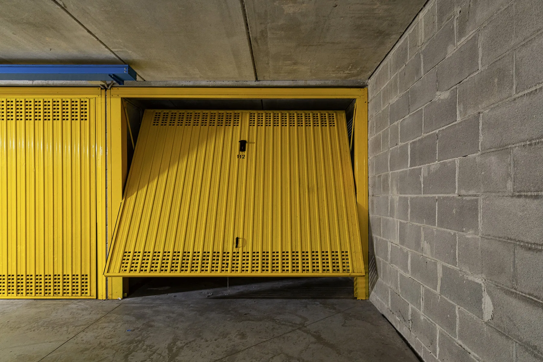 Una zona de garaje con puertas metálicas amarillas junto a una pared de hormigón.