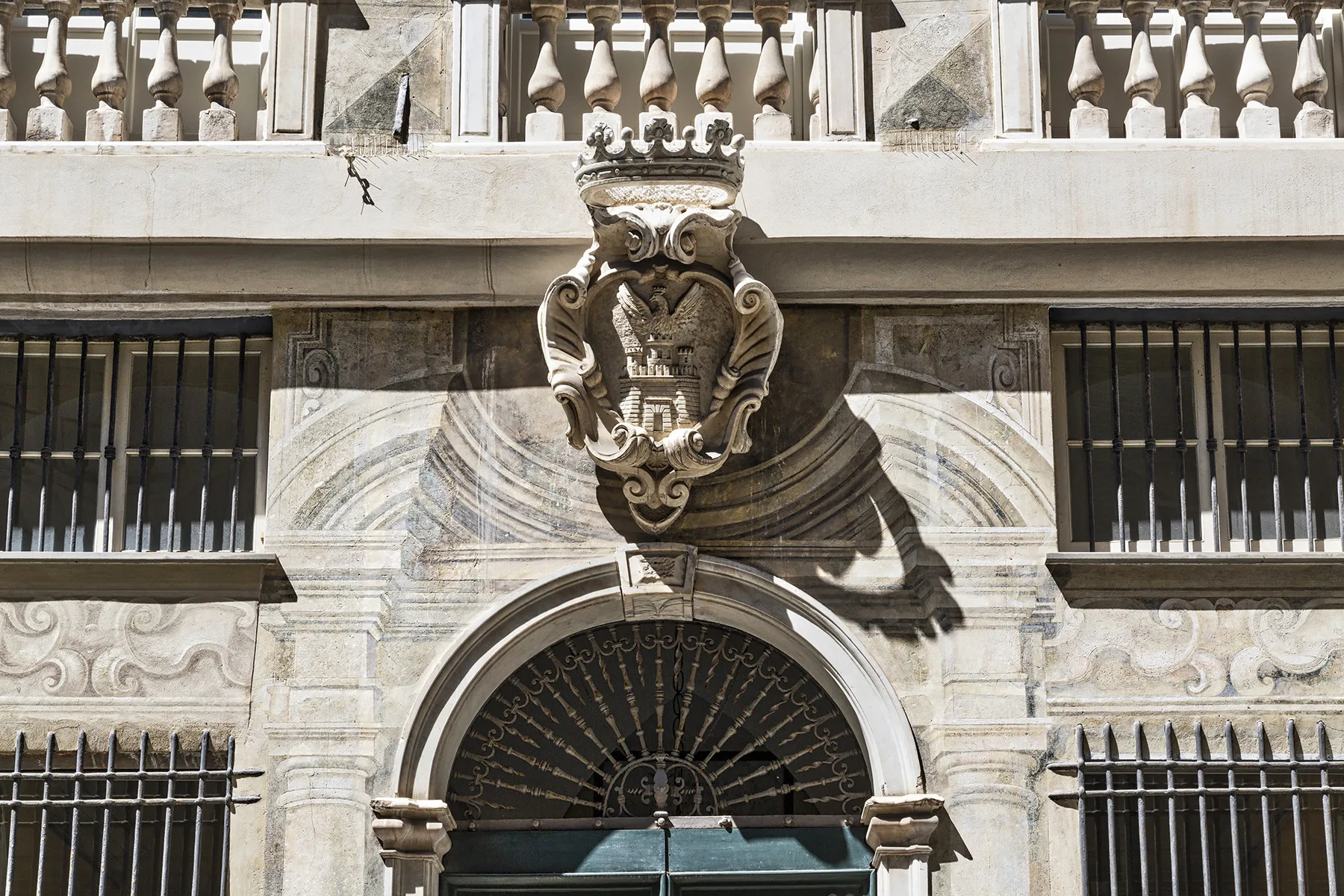 Una fachada de piedra presenta un escudo ornamentado sobre una entrada arqueada.