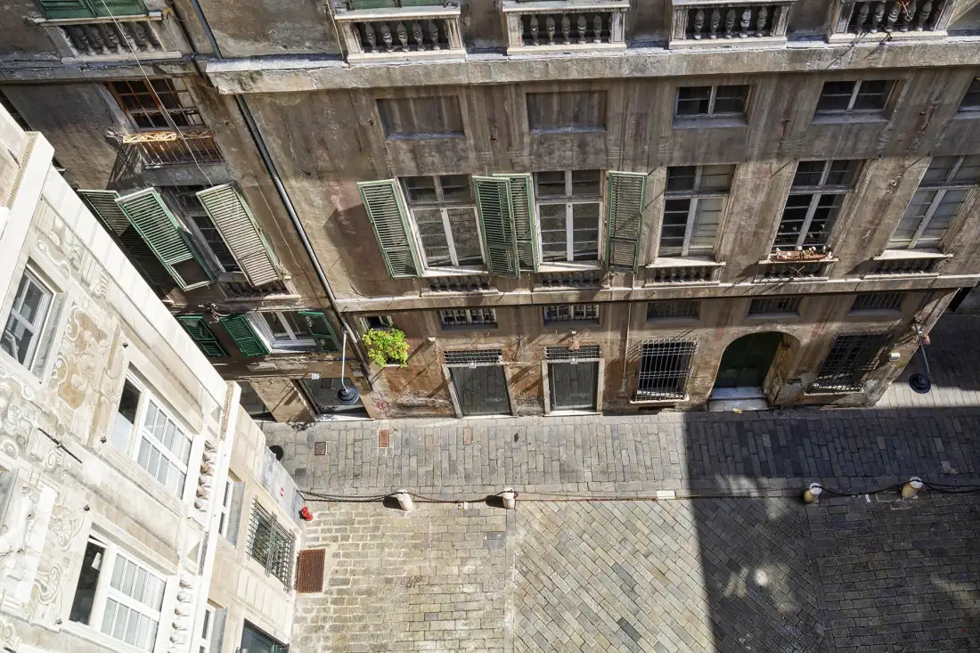 Una calle empedrada pasa entre edificios altos con ventanas con contraventanas.