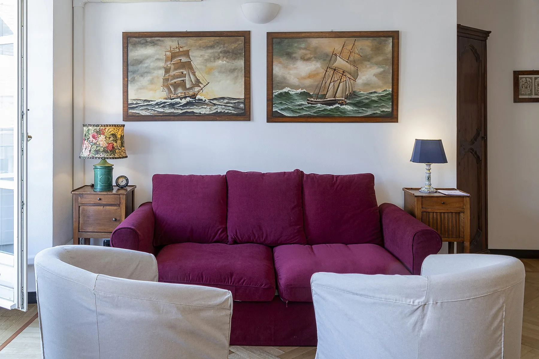 Una sala de estar con un sofá magenta frente a dos sillones claros.