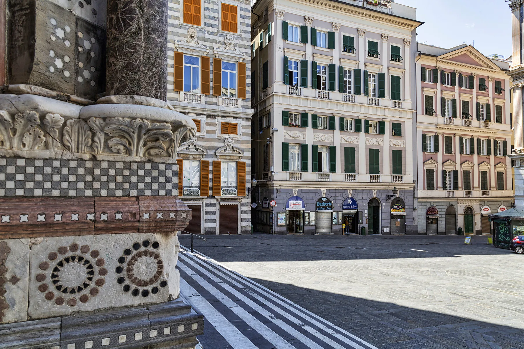 Una plaza urbana pavimentada con edificios históricos ornamentados y piedra decorativa.