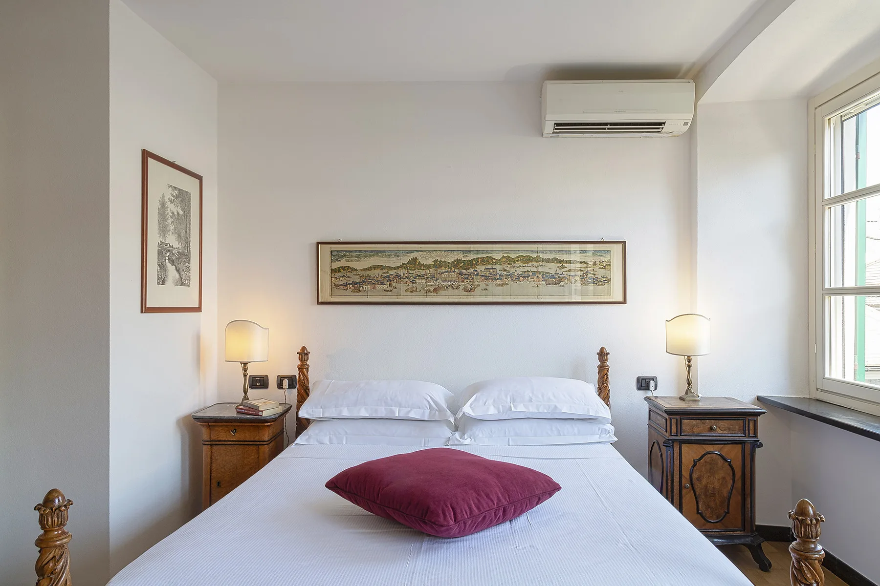 Un dormitorio con una cama blanca, mesas de noche y cuadros en las paredes.