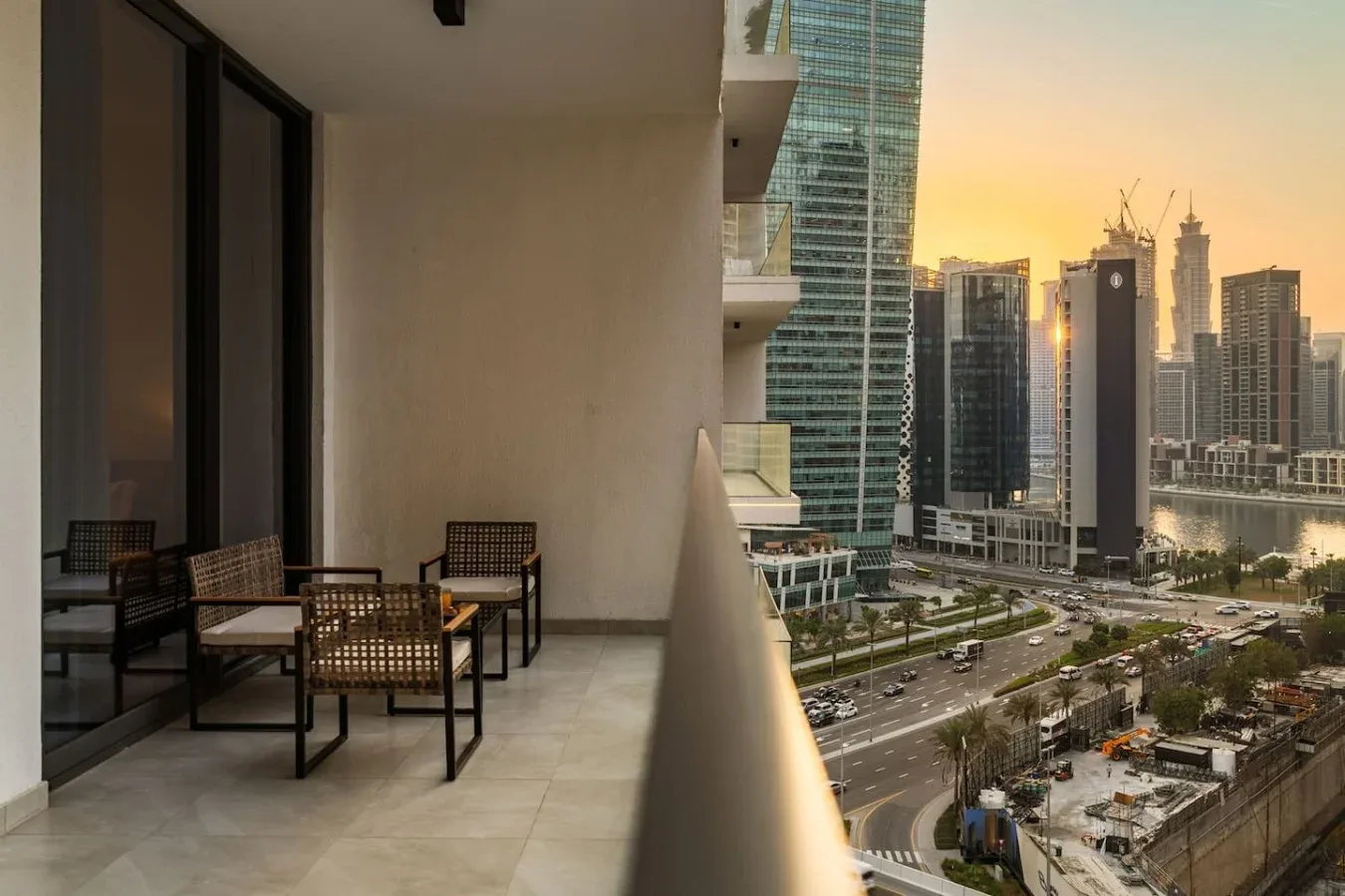 A balcony seating area overlooks a city skyline at sunset.