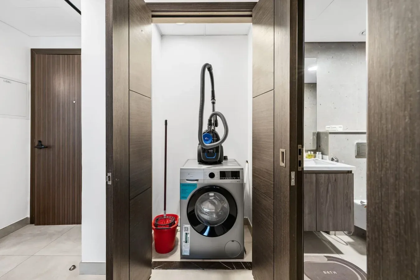 A laundry area with a front-loading washing machine and vacuum cleaner.