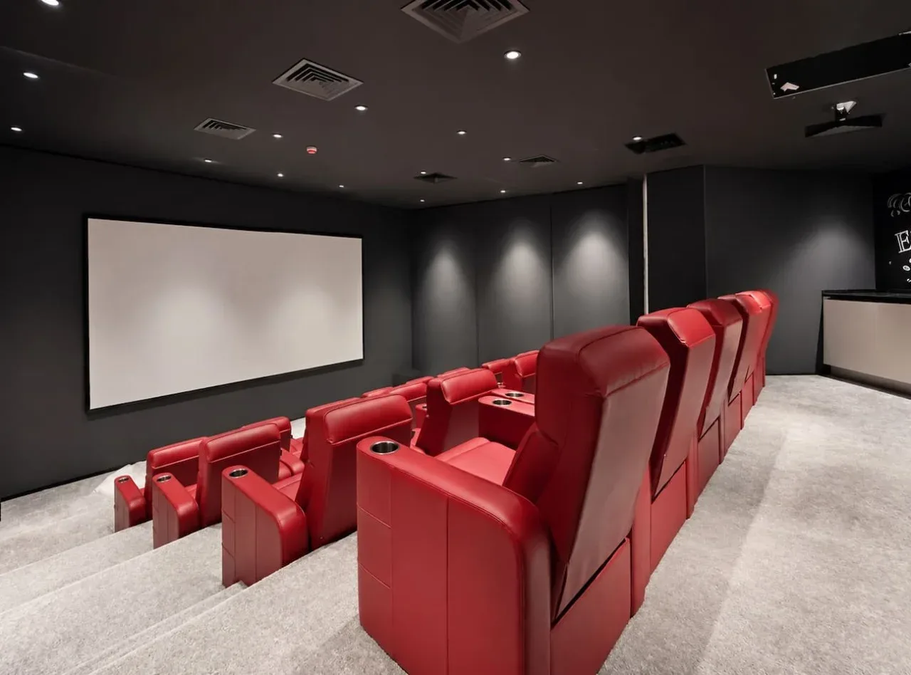 A small theater with rows of red seating facing a blank screen.
