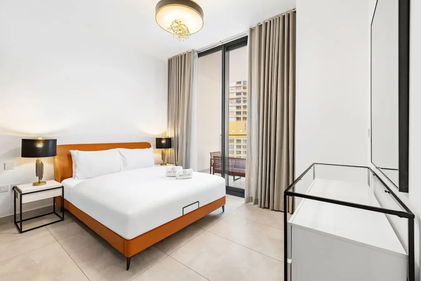 A bedroom with a bed beside a glass door and curtains.