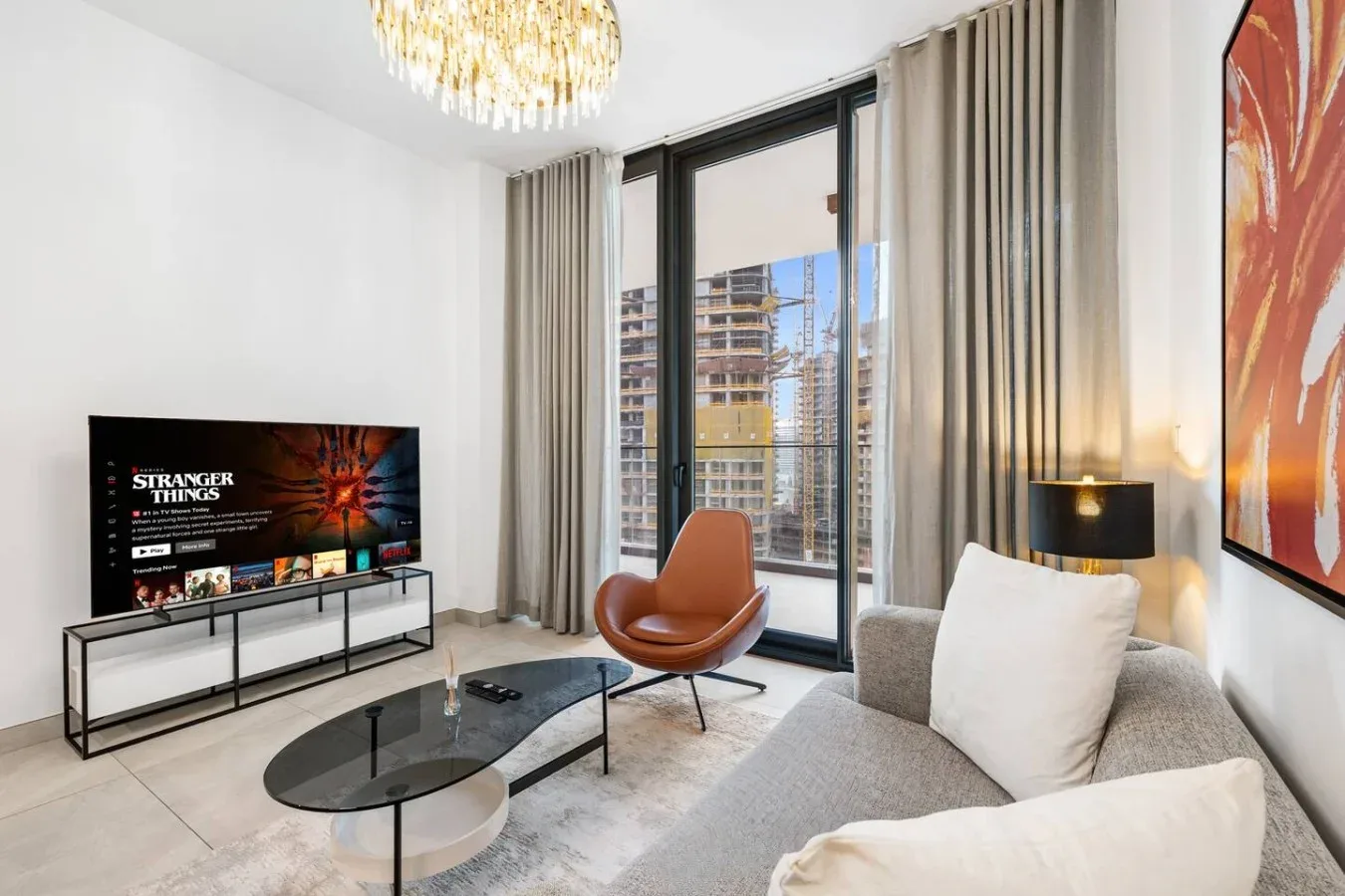 A modern living room with seating, a television, and large windows.
