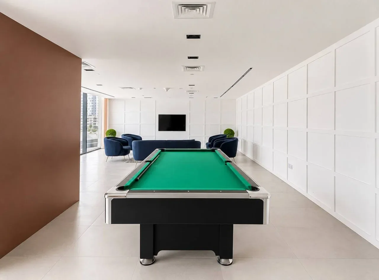 A billiards room with a green-felt pool table and seating.