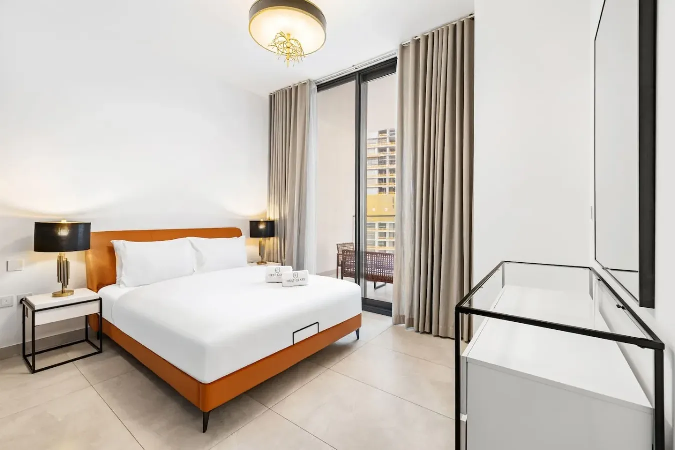 A bright bedroom with a white bed and floor-to-ceiling curtains beside a glass door.