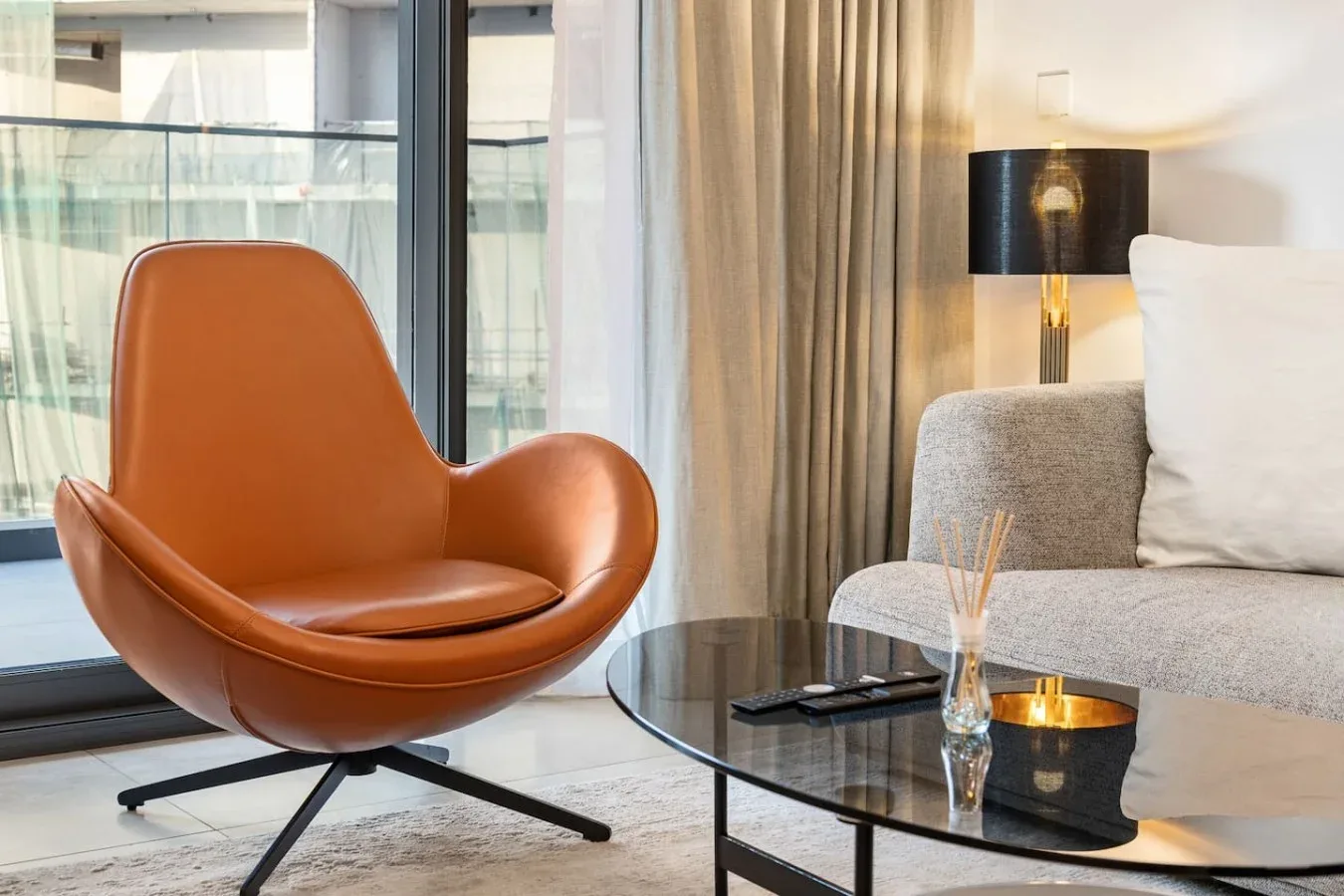 A living room with a sculptural leather chair beside a glass coffee table.