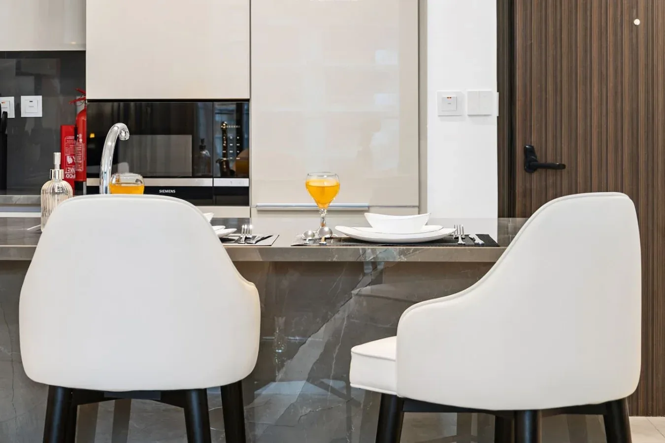 A modern dining area with white seating and a set table.