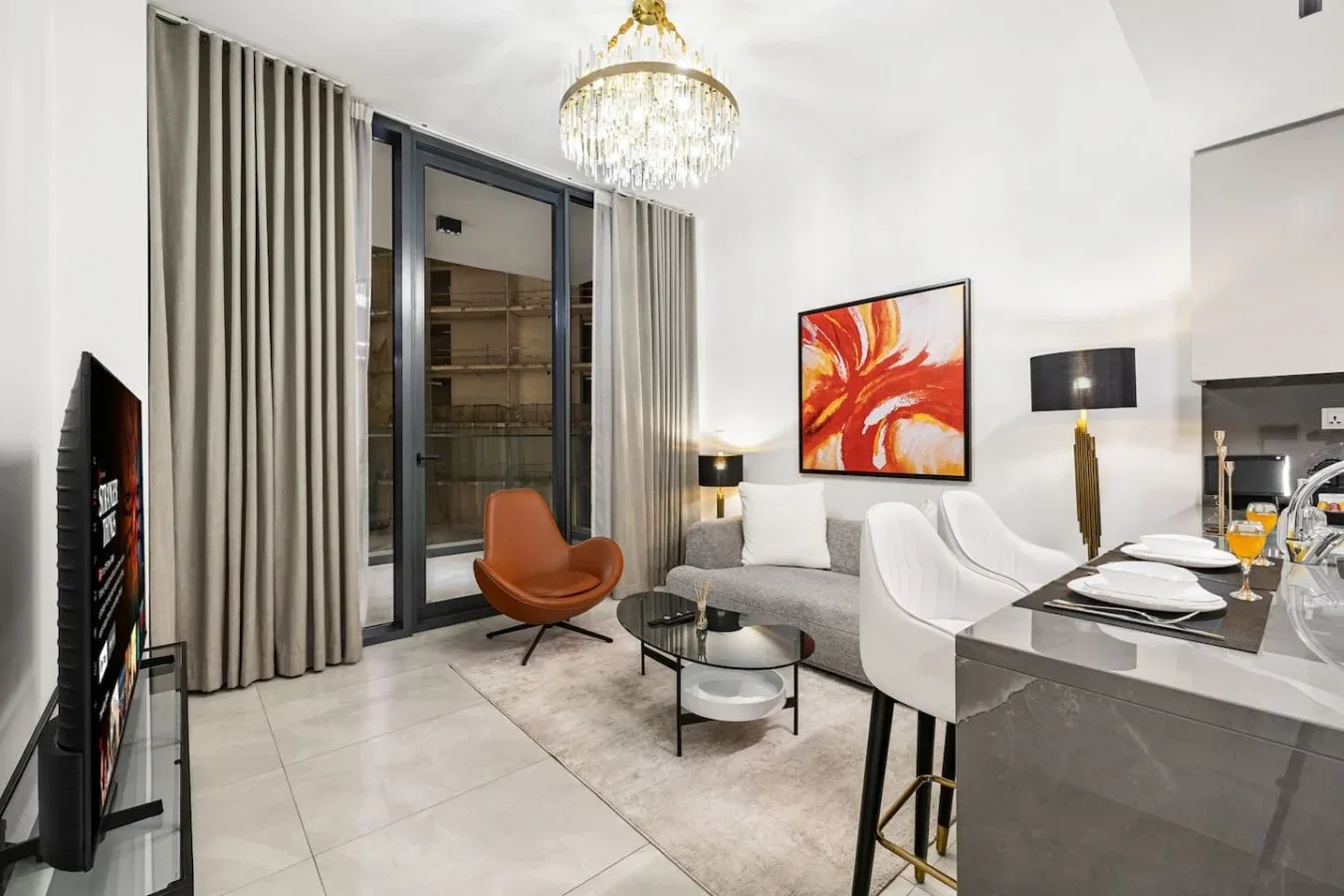 A bright living and dining area features a seating group beside a kitchen counter.