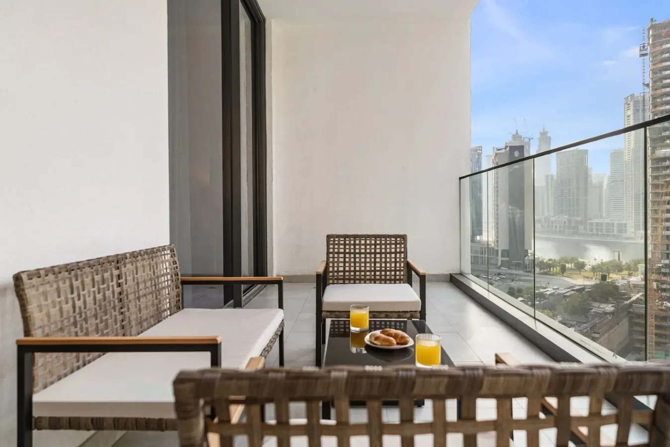 A balcony seating area with a glass railing overlooking the city.