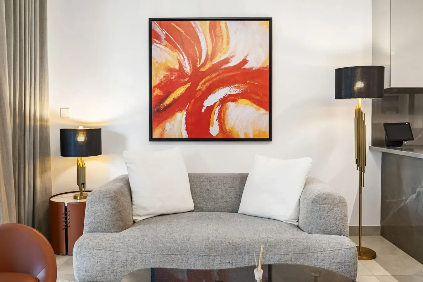 A living room with a gray sofa beneath a bright abstract painting.
