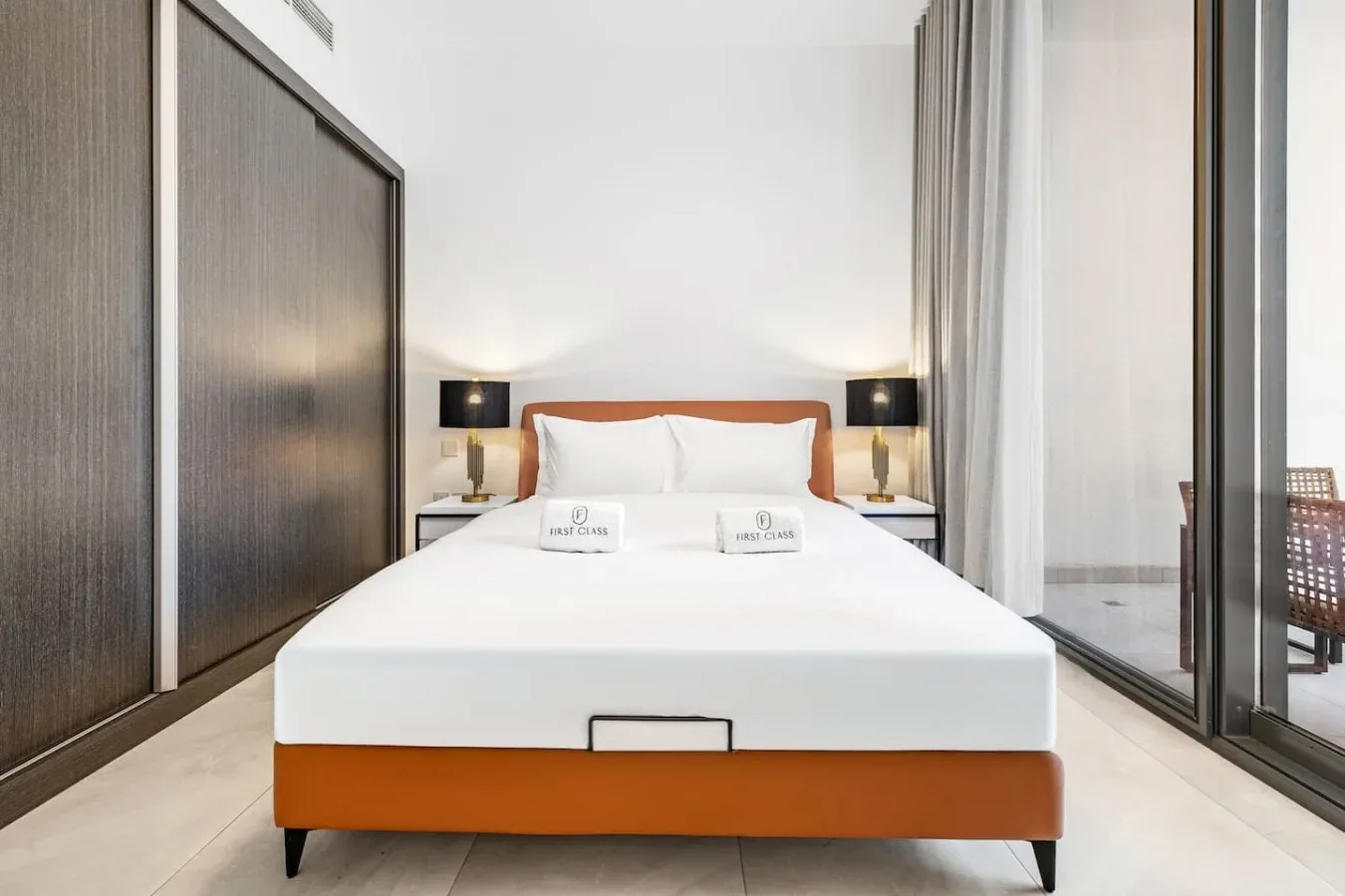 A bedroom with a neatly made bed and matching bedside lamps.