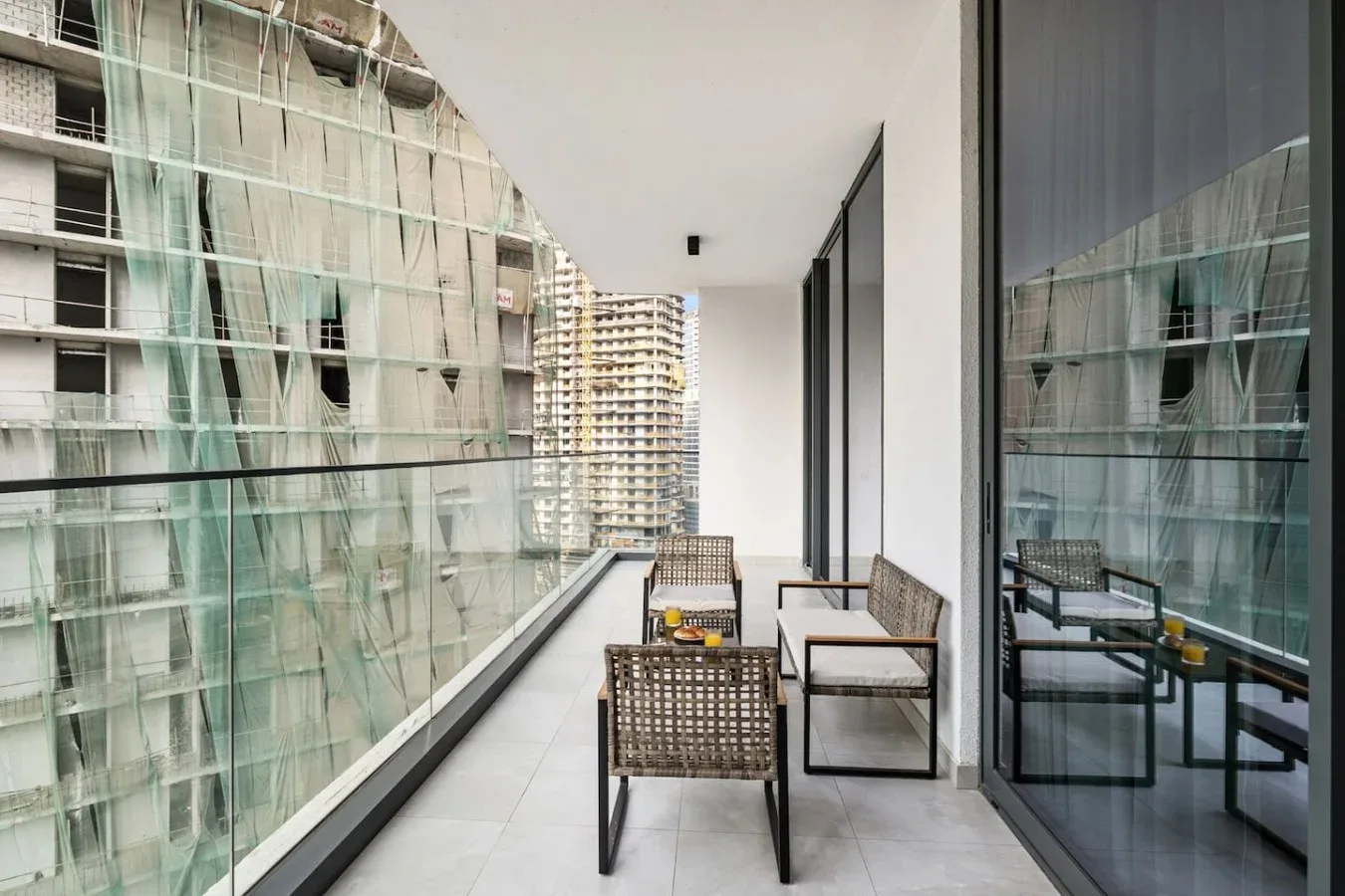 A balcony with outdoor seating overlooks neighboring apartment buildings.