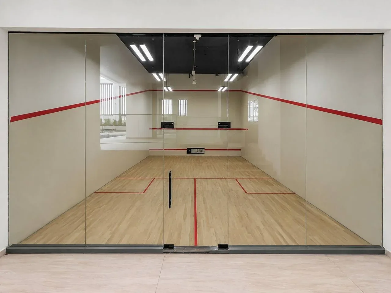 A glass-enclosed squash court with a wooden floor and red boundary lines.