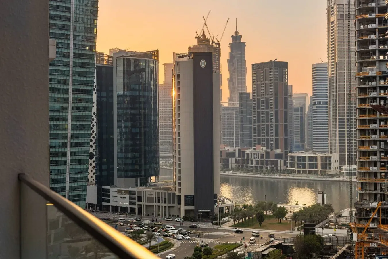 Horizonte urbano y paseo junto al agua vistos desde un balcón al atardecer.
