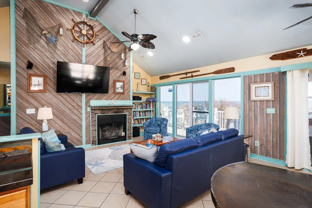 Una sala de estar con asientos azules, una chimenea y ventanas grandes.