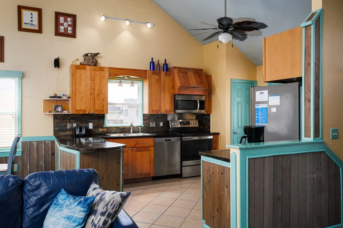 Cocina y sala de estar de concepto abierto con molduras turquesas y asientos azules.