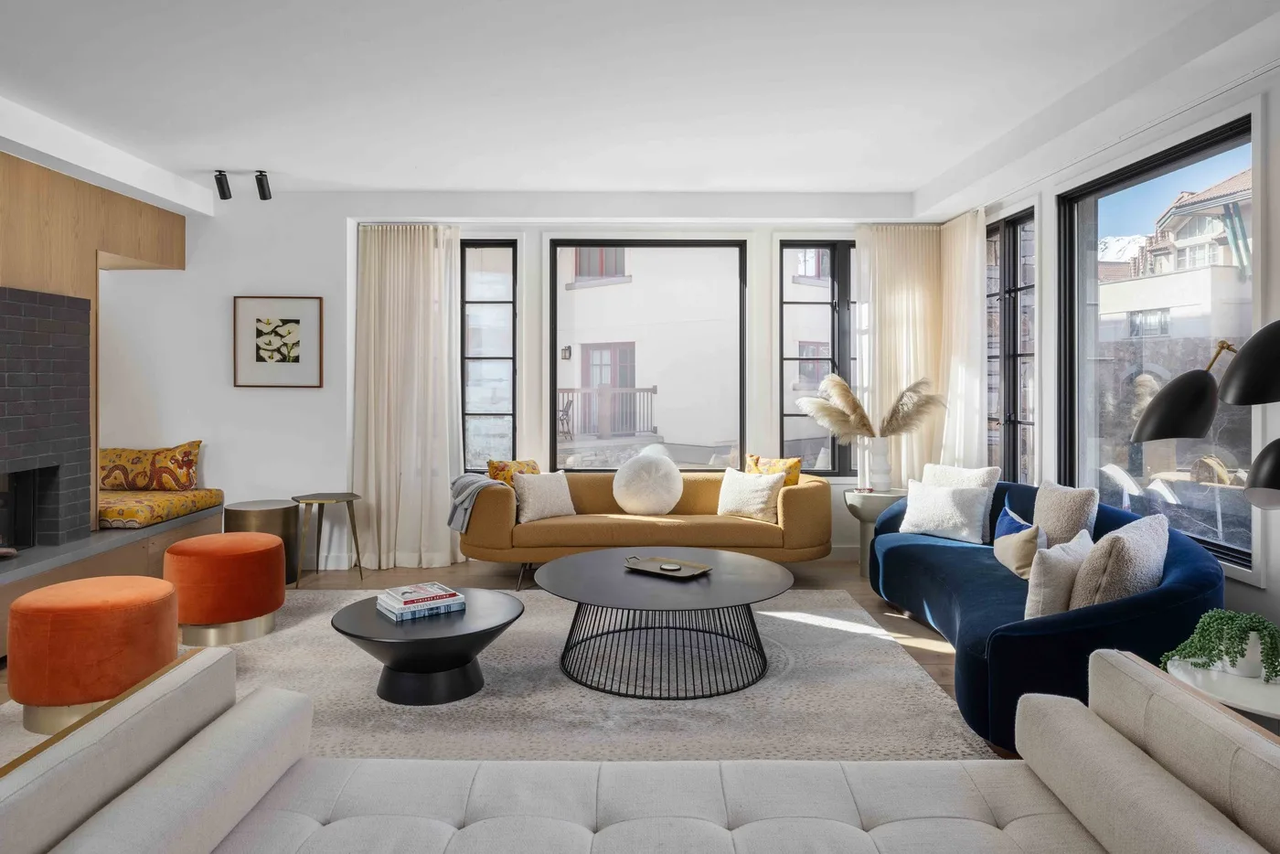 A bright living room with sofas, armchairs, and round coffee tables.
