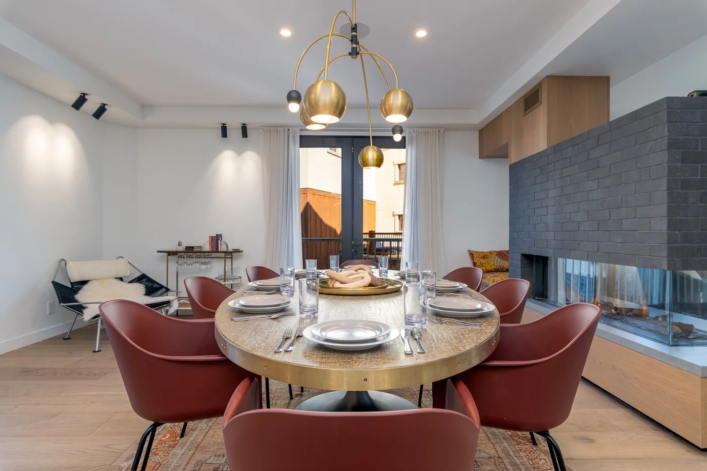 Comedor con una mesa redonda puesta bajo lámparas colgantes.