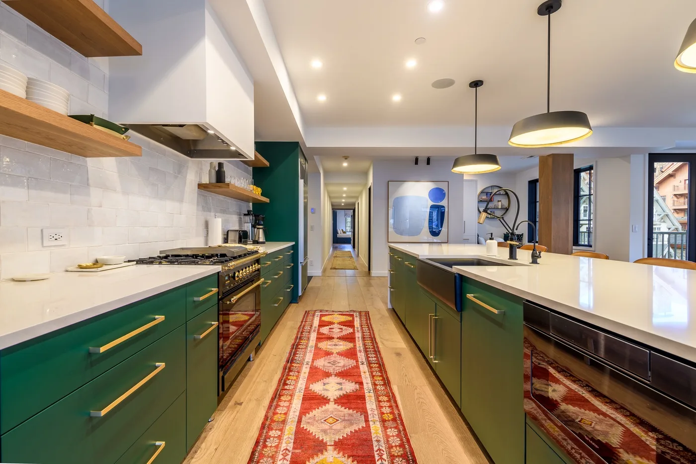 Una cocina moderna con gabinetes verdes, una isla central y un camino estampado.