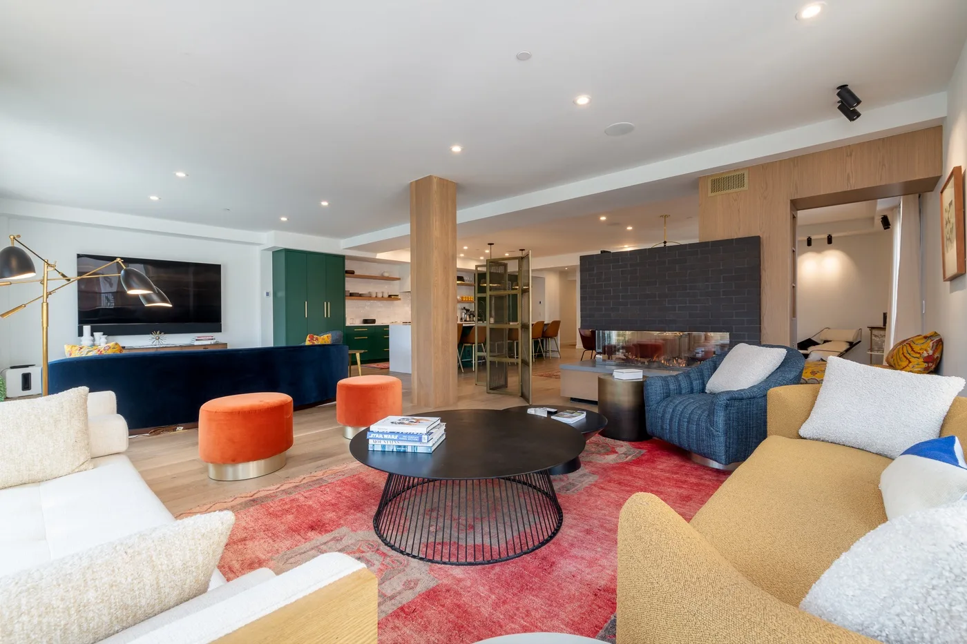 Una amplia sala de estar con distintos asientos alrededor de una mesa de centro y una alfombra colorida.
