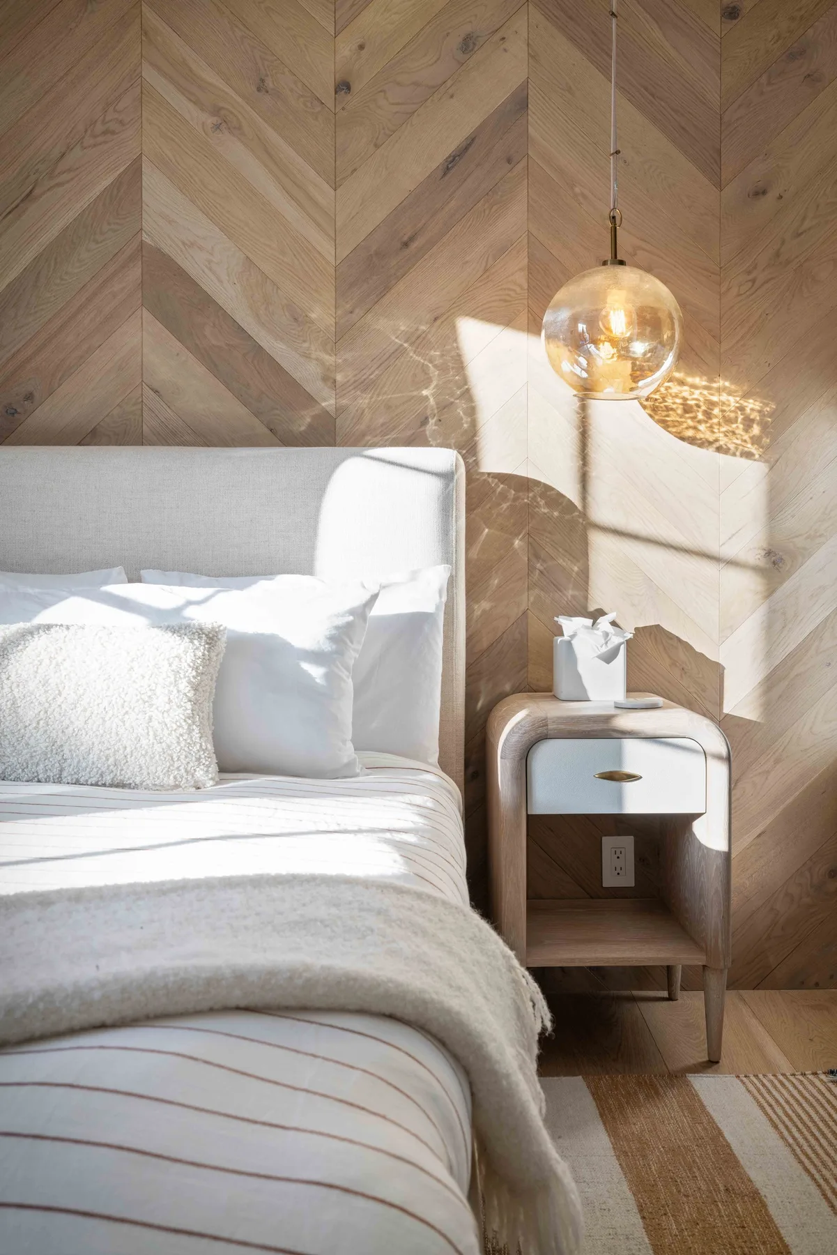 Un dormitorio luminoso con una cama tendida y una pequeña mesita de noche.