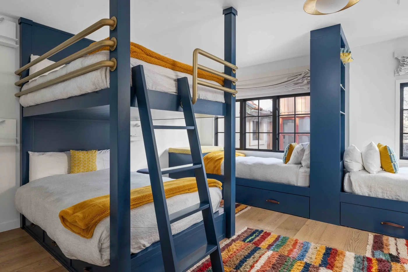 Un dormitorio con literas empotradas, ropa de cama blanca y una alfombra colorida.
